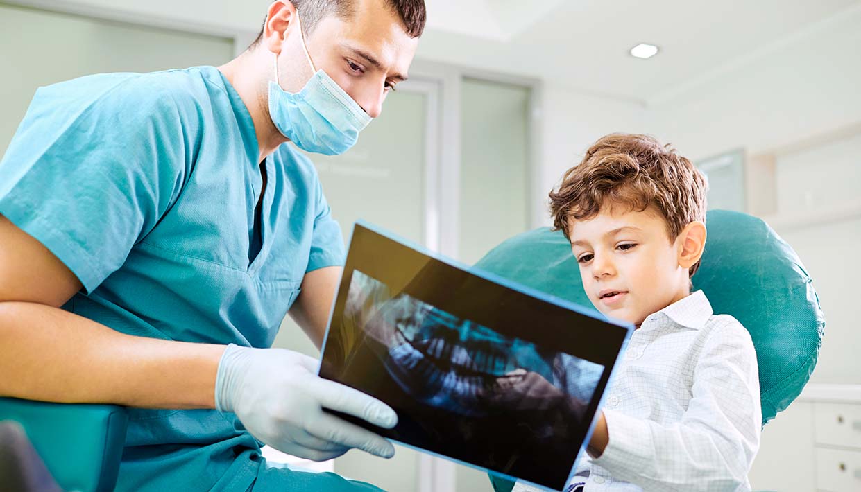 Zahnarzt und Kind schauen auf ein Röntgenbild
